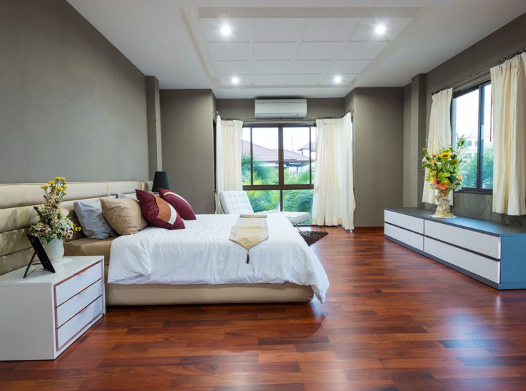 A bedroom with hard wood floors and white walls.