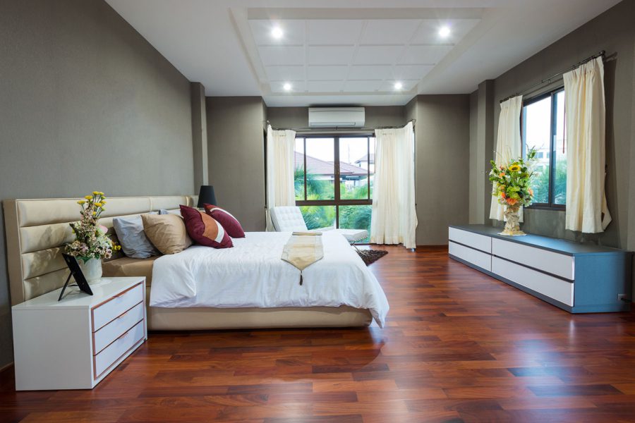 A bedroom with hard wood floors and white walls.