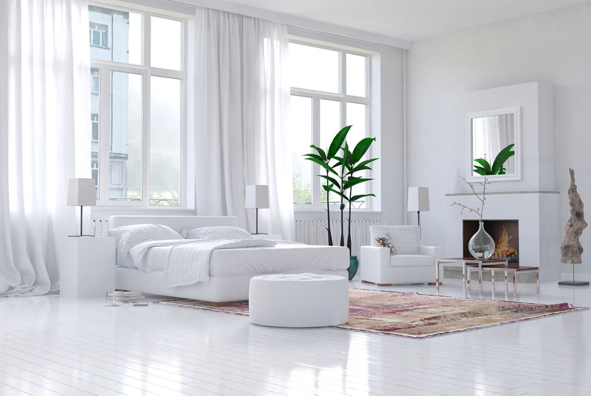 A white bedroom with a large bed and a plant.