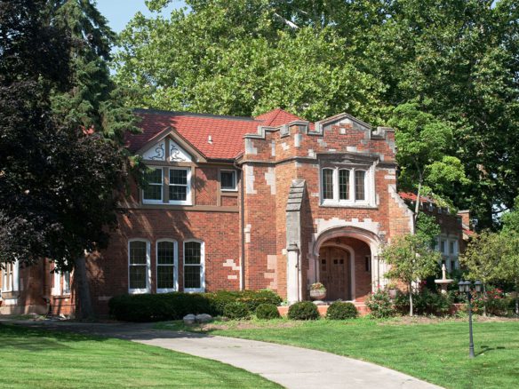 A brick house with a large lawn in front of it.