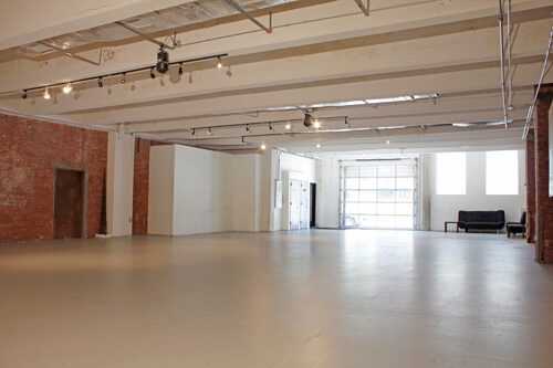 A large empty room with white floors and brick walls.