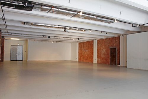 A large empty room with exposed brick and white walls.