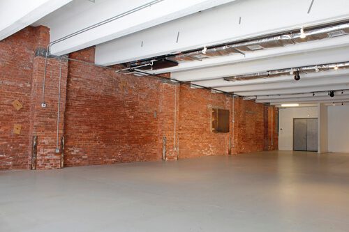 A large empty room with brick walls and concrete floors.