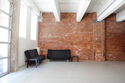 A room with two black chairs and a brick wall