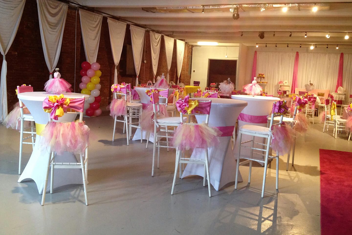 A room with chairs and tables decorated in pink