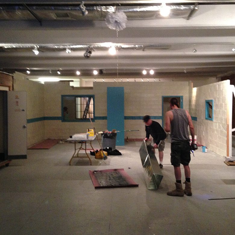 Two men are working in a room with unfinished walls.
