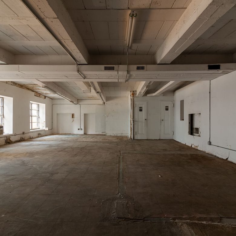 A large empty room with white walls and concrete floors.