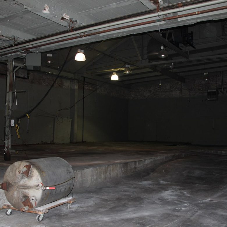 A large concrete room with lights and a barrel.