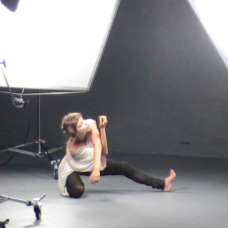 A woman is sitting on the ground in front of a camera.