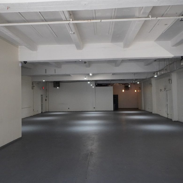 A large empty room with white walls and black floors.
